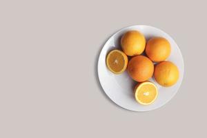 frutas frescas de laranjas em um prato branco para o menu. fundo geométrico. postura plana, cópia espaço, vista superior. foto