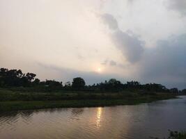 a Sol é configuração sobre uma rio dentro a distância foto