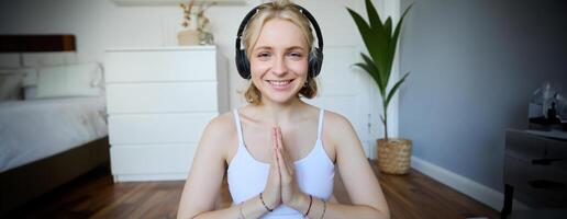 bem estar e pessoas conceito. fechar acima retrato do jovem mulher dentro fones de ouvido, meditando, prática ioga, escuta para podcast dentro fones de ouvido foto