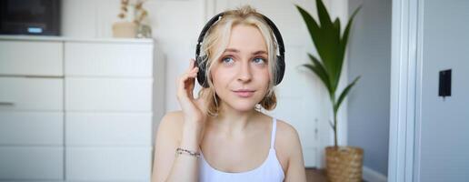 conceito do pessoas e estilo de vida, fechar acima do lindo loiro mulher dentro sem fio fones de ouvido, escuta para música, goza Boa qualidade som dentro Novo fones de ouvido foto