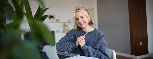 retrato do jovem sorridente mulher, aluna falando para professor conectados através da bater papo, fazendo curso, atende controlo remoto curso dentro Internet, fazer notas foto