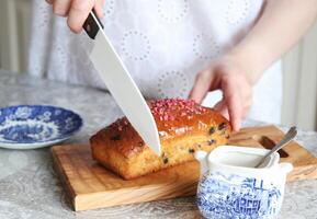 fechar acima do mulher dentro branco vestir corte Bolinho com cerâmico faca dentro cozinha. foto