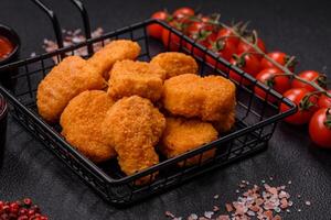 deliciosos nuggets de frango crocantes frescos em um fundo escuro de concreto foto