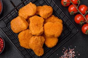 deliciosos nuggets de frango crocantes frescos em um fundo escuro de concreto foto