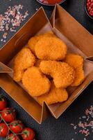 deliciosos nuggets de frango crocantes frescos em um fundo escuro de concreto foto