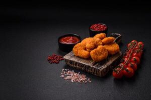 deliciosos nuggets de frango crocantes frescos em um fundo escuro de concreto foto