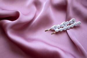 lindo pérola grampo em Rosa seda fundo. adequado para vários jóias lojas e moda anúncios. foto