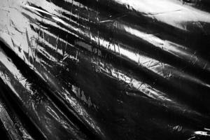 um filme plástico transparente em fundo preto. textura de envoltório plástico realista para sobreposição e efeito. padrão de plástico enrugado para design criativo e decorativo. foto