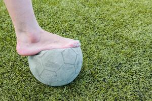 menina descalço e velho futebol bola foto