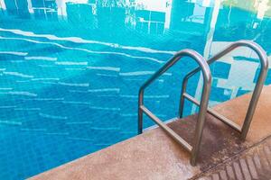 escada com barras de apoio na piscina azul foto