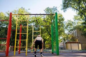 uma Esportes criança realizado com uma saltar a partir de a barra. rua exercite-se em uma horizontal Barra dentro a escola parque. foto