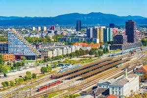 panorama aéreo de Liubliana com edifícios modernos, a principal estação ferroviária, trens e belas colinas verdes ao fundo, Eslovênia foto