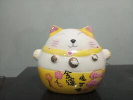 uma cerâmico gato estatueta com uma amarelo e branco Projeto foto