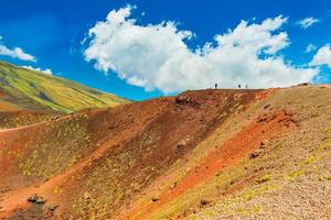 belas colinas de lava coloridas com grupo de pessoas caminhando para uma cratera vulcânica. monte etna, sicília, itália foto