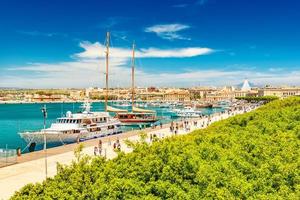 bela vista do porto de Siracusa com pessoas caminhando ao longo do calçadão. paisagem urbana da ilha ortygia, sicília, itália foto