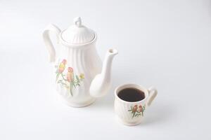 uma copo do doce chá com uma cerâmico chaleira com uma pássaro em uma branco fundo foto