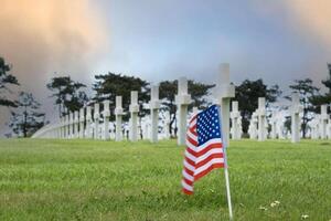 americano cemitério às normandia área. bandeira dentro primeiro plano do sepultura pedras. segunda guerra mundial memorial. foto