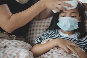 uma mulher é ajudando uma criança com uma febre foto