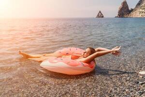 verão período de férias mulher flutua em a inflável rosquinha colchão, uma água brinquedo nadar anel. positivo feliz mulher relaxante e desfrutando família verão viagem feriados período de férias em a mar. lento movimento foto