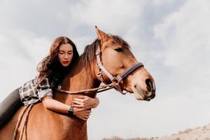 jovem feliz mulher dentro chapéu com dela cavalo dentro tarde pôr do sol claro. ao ar livre fotografia com moda modelo garota. estilo de vida humor. conceito do ao ar livre cavalgando, Esportes e lazer. foto