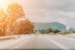 uma rural estrada com uma carro dirigindo baixa isto foto