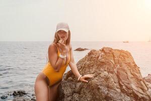 mulher viagem mar. feliz turista dentro chapéu apreciar levando cenário ao ar livre para recordações. mulher viajante posando em a de praia às mar cercado de vulcânico montanhas, partilha viagem aventura viagem foto