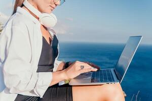 mulher mar computador portátil. o negócio mulher, trabalhador autonomo com computador portátil trabalhando sobre azul mar de praia. feliz sorridente menina alivia estresse a partir de trabalhar. freelance, controlo remoto trabalhos em férias, digital nômade, viagem conceito foto