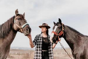 jovem feliz mulher dentro chapéu com dela cavalo dentro tarde pôr do sol claro. ao ar livre fotografia com moda modelo garota. estilo de vida humor. conceito do ao ar livre cavalgando, Esportes e lazer. foto