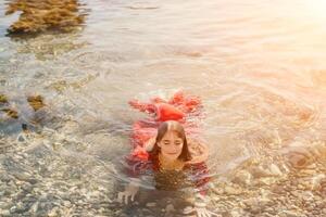 mulher viagem mar. feliz turista dentro vermelho vestir apreciar levando cenário ao ar livre para recordações. mulher viajante posando dentro mar praia, cercado de vulcânico montanhas, partilha viagem aventura viagem foto