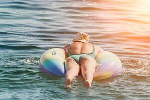 verão período de férias mulher flutua em a inflável rosquinha colchão, uma água brinquedo nadar anel. positivo feliz mulher relaxante e desfrutando família verão viagem feriados período de férias em a mar. lento movimento foto