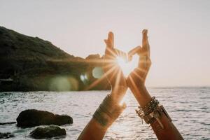 mulher mar ioga. feliz mulher dentro branco roupa de banho e boho estilo braquetes praticando ao ar livre em ioga esteira de mar em pôr do sol. mulheres ioga ginástica rotina. saudável estilo de vida, harmonia e meditação foto