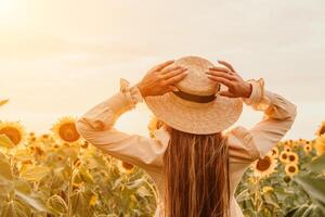 mulher dentro girassol campo. feliz menina dentro uma Palha chapéu posando dentro uma grande campo do girassóis às pôr do sol, apreciar levando cenário ao ar livre para recordações. verão tempo. foto