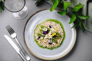 gourmet risoto com comestível flores em elegante mesa configuração foto