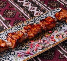 tradicional grelhado carne espetos em ornamentado prato foto