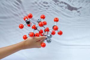 mão segurando uma simular forma do covalente moléculas em uma cinzento e branco fundo. foto