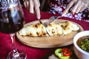 pessoa corte uma peça do Comida com uma faca e garfo foto