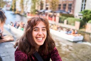 uma menina dentro uma vermelho veludo cotelê vestir com a aberto costas anda em através a ruas do Bruges em a outono dia foto