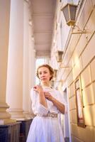 elegante meio era mulher dentro branco vintage vestir perto teatro com Antiguidade colunatas foto