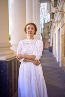 elegante meio era mulher dentro branco vintage vestir perto teatro com Antiguidade colunatas foto