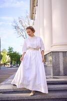 elegante meio era mulher dentro branco vintage vestir perto teatro com Antiguidade colunatas foto