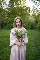 uma retrato do uma lindo jovem mulher com uma ramalhete do lilases foto