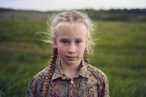 retrato do uma pequeno loiro menina dentro uma campo foto