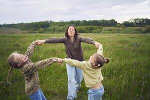 uma mãe e dois irmãs círculo dentro a campo segurando mãos foto