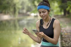 saudável mulher sentado depois de exercício dentro parque e ouvindo música foto