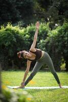 Maravilhoso senhora praticando trikonasana ioga pose dentro jardim foto