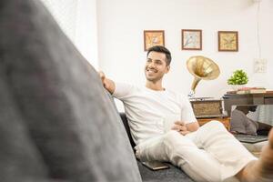 bonito Loiras homem relaxante em sofá segurando café caneca dentro mão e pensando alguma coisa foto