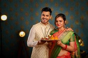 cenário do indiano casal dentro tradicional vestuário para a diwali festival carregando pooja prato dentro seus mãos foto