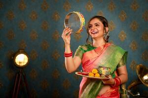 feliz esposa dentro saree segurando pooja prato dentro mão durante karva Chauth festival foto