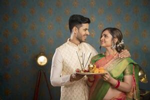 dentro isto estoque imagem a partir de a diwali festival, uma perfeito casal é segurando pratos e olhando às cada de outros foto