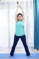 mulher dentro Academia engrenagem fazendo meditação ioga levantando dela mãos acima foto